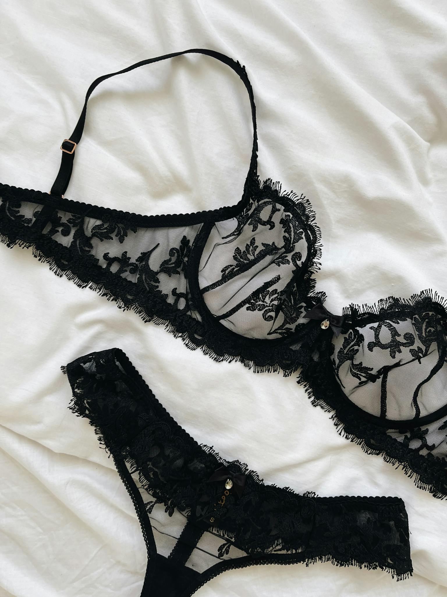 Black lace bra and panties set elegantly laid on white sheets, displaying delicate design.